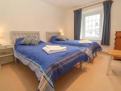 two beds in a room with blue sheets and towels at Fair View in Truro