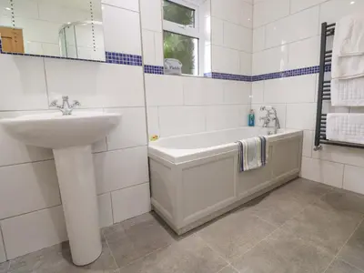 a white bathroom with a sink and a bath tub at Fair View in Truro
