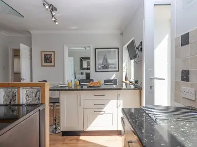 a kitchen with white cabinets and a black counter top at Seahaze in Torpoint