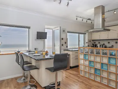 a kitchen with a large island with chairs and windows at Seahaze in Torpoint