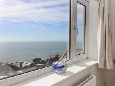 a vase sitting on a window sill looking out at the ocean at Seahaze in Torpoint