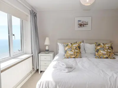 a bedroom with a white bed with a window at Seahaze in Torpoint