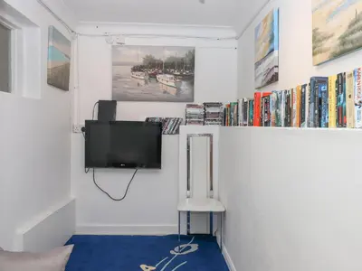 a room with a tv on a wall with books at Seahaze in Torpoint