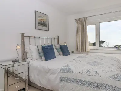 a bedroom with a bed with blue pillows and a window at Seahaze in Torpoint