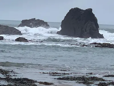 a group of rocks in the ocean with waves at TREKLYS Shepherds Hut in Otterham