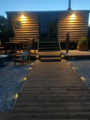 a wooden walkway leading to a cabin at night at TREKLYS Shepherds Hut in Otterham