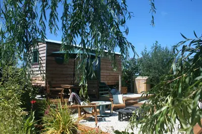 a backyard with a cabin with a table and chairs at TREKLYS Shepherds Hut in Otterham
