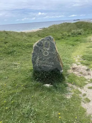 a rock sitting on the grass next to the beach at Trees Dale Lodge in Hayle in Hayle