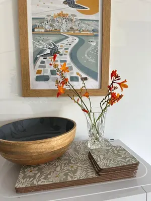 a vase with flowers on a table with a painting at Trees Dale Lodge in Hayle in Hayle