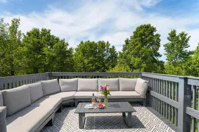 a patio with a couch and a table on a deck at The Little Hawthorns in Polzeath
