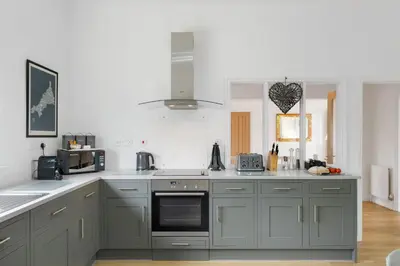 a kitchen with gray cabinets and a stove top oven at The Little Hawthorns in Polzeath