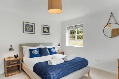 a bedroom with a bed with blue and white pillows at The Little Hawthorns in Polzeath