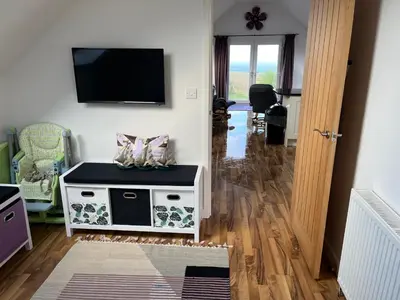 a living room with a flat screen tv on a wall at Sunnyridge Cottage, Porthcothan Bay in Saint Ervan