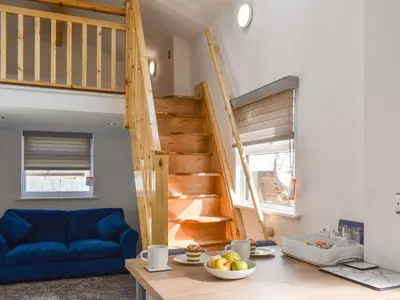 a living room with a blue couch and stairs at The Boat House in Padstow