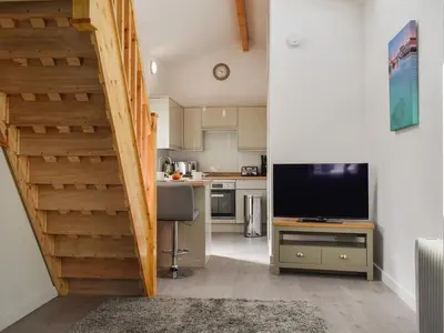 a living room with a staircase and a television at The Boat House in Padstow