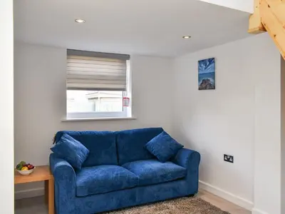 a blue couch in a living room with a window at The Boat House in Padstow