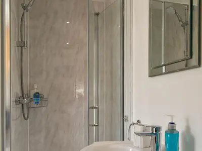 a bathroom with a shower and a sink and a mirror at The Boat House in Padstow
