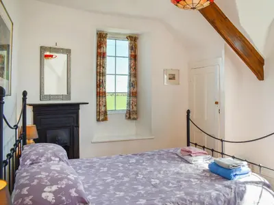 a bedroom with a bed and a fireplace and a window at Nessa Cottage - Uk47087 in Davidstow