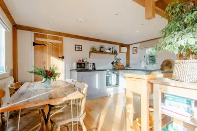a kitchen with a wooden table and a dining room at Little Trenant Barn on Helford River Near Constantine in Constantine