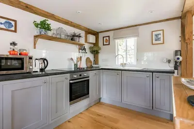 a kitchen with white cabinets and black counter tops at Little Trenant Barn on Helford River Near Constantine in Constantine