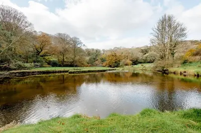 a pond in a park with trees and a river at Little Trenant Barn on Helford River Near Constantine in Constantine
