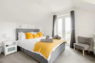a bedroom with a large bed and a chair at Ashwood bed and breakfast in Truro