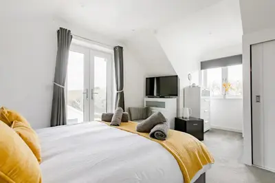 a white bedroom with a large bed and a tv at Ashwood bed and breakfast in Truro