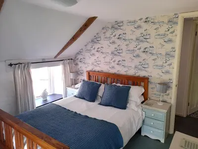 a bedroom with a bed with blue pillows on it at Waterside Cottage in Penzance
