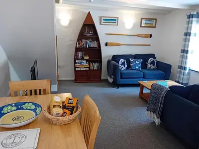 a living room with a blue couch and a table at Waterside Cottage in Penzance