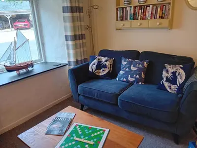 a living room with a blue couch and a table at Waterside Cottage in Penzance