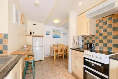 a kitchen with a sink and a stove top oven at Waterside Cottage in Penzance