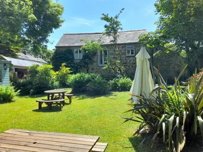 a garden with a picnic table and an umbrella at Waterside Cottage in Penzance