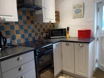 a kitchen with a stove and a microwave at Waterside Cottage in Penzance