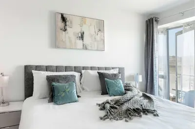 a bedroom with a white bed with blue pillows at 6 Azure, Newquay in Newquay
