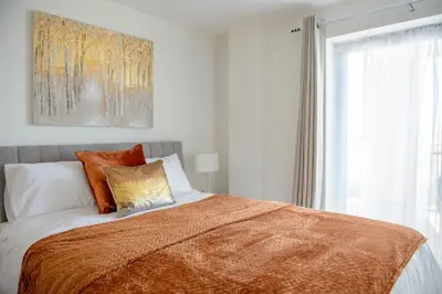a bedroom with a bed with an orange blanket at 6 Azure, Newquay in Newquay