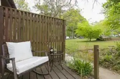 a wooden deck with a chair and a table at Rebels Retreat - 2-Bed Chalet nr St Ives & Hayle in St Ives