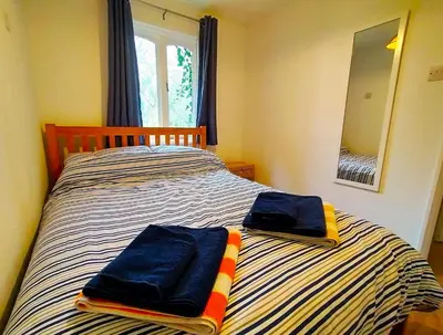 a bedroom with two towels on a striped bed at Rebels Retreat - 2-Bed Chalet nr St Ives & Hayle in St Ives