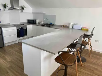 a kitchen with a large white counter and two chairs at Truro City Escape (self contained apartment) in Truro