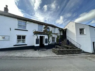 a white house with a staircase in front of it at The Ship Inn Lerryn in Lerryn