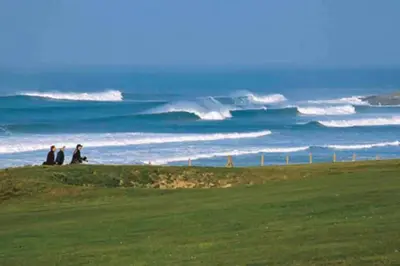 three people sitting on a hill looking at the ocean at Palms 1 Log Burner Private Courtyard Parking Central Newquay in Newquay