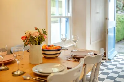 a dining room table with a vase of flowers and wine glasses at 5 Bed in Little Petherick oc-melynw in Little Petherick