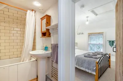 a bedroom with a bed and a sink and a tub at 5 Bed in Little Petherick oc-melynw in Little Petherick