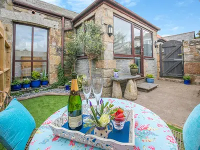 a table with a bottle of wine and two glasses at Riverside Barn in Newquay