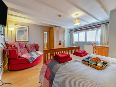 a bedroom with a bed and a red couch at Riverside Barn in Newquay