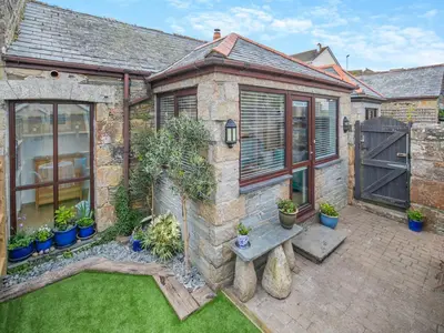 an old brick house with a garden with potted plants at Riverside Barn in Newquay
