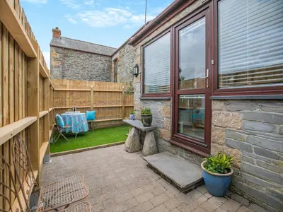 a patio with a table and a bench next to a building at Riverside Barn in Newquay