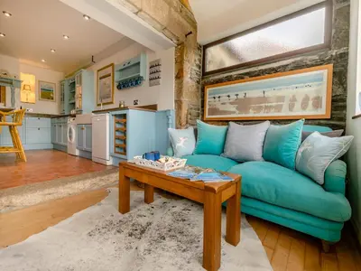a living room with a blue couch and a table at Riverside Barn in Newquay