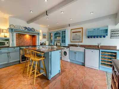 a large kitchen with blue cabinets and a dishwasher at Riverside Barn in Newquay