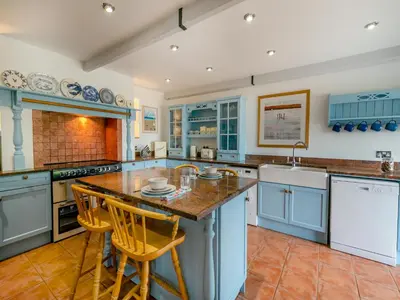 a kitchen with blue cabinets and a island with bar stools at Riverside Barn in Newquay