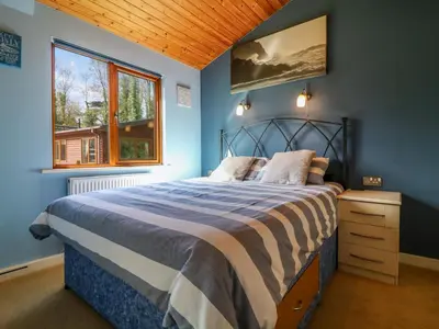a bedroom with a bed with blue walls and a window at 3 The Glade in Wadebridge